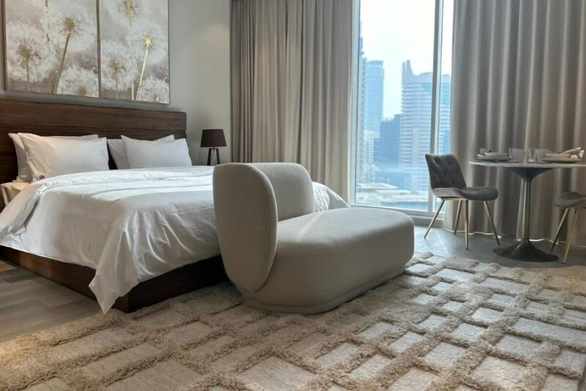 Ein modernes Hotelzimmer mit einem großen Bett, einer Sitzecke mit Tisch und Blick auf die Stadt.