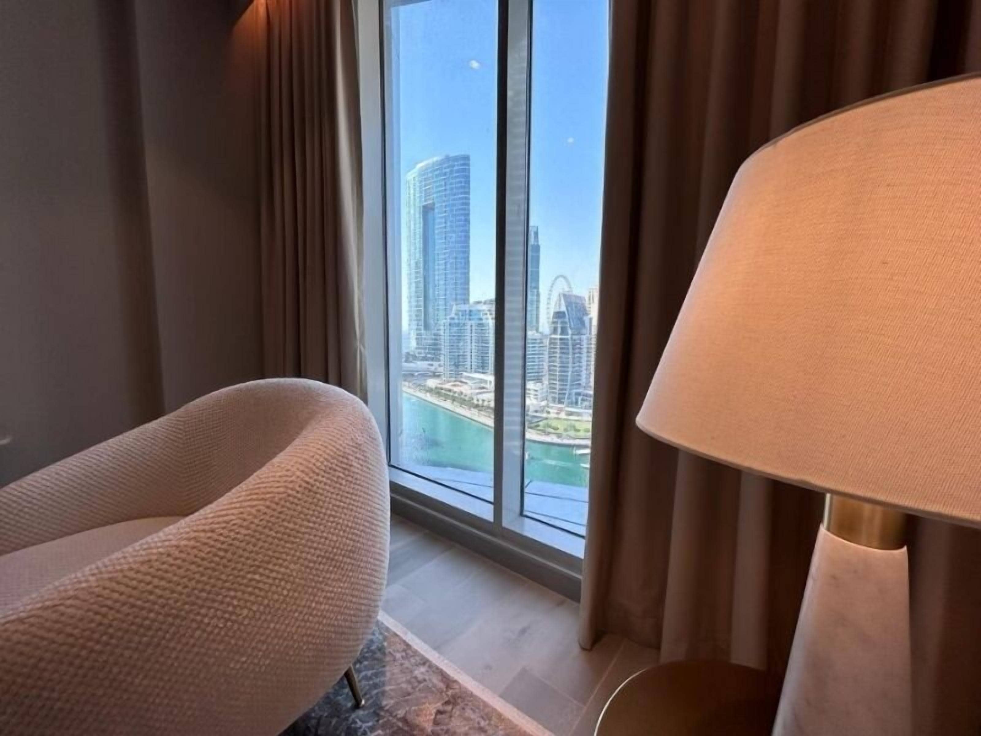 A modern room with a large window offering a view of a city skyline and a body of water.