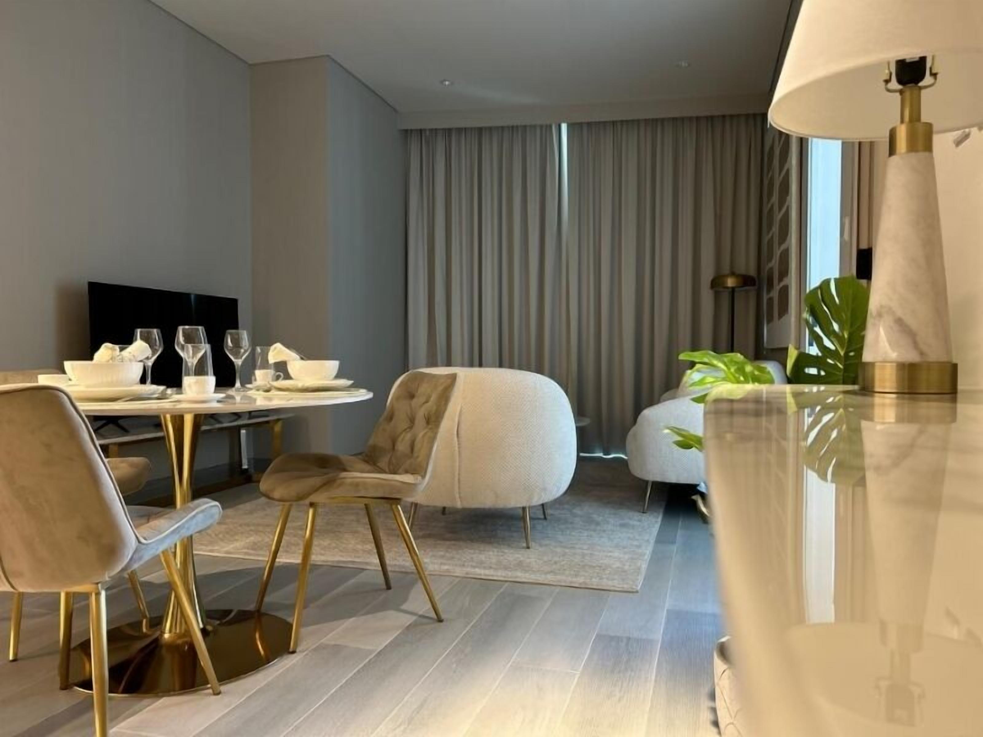 A modern hotel room with a dining area, a sofa, and a lamp.