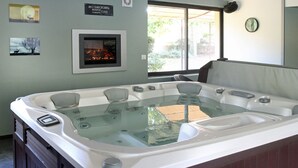 Un jacuzzi con vistas al exterior, un cartel de 'No Smoking', cuadros enmarcados en la pared y un reloj.