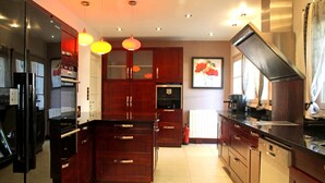 Una cocina moderna con armarios de madera oscura, electrodomésticos de acero inoxidable e iluminación colgante.
