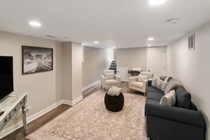 A living room with a sofa, armchairs, a coffee table, and a flat-screen TV. - Great For Families DT Libertyville near Naval Base (Libertyville)