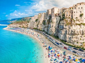 Une ville côtière dotée d’une plage bordée de parasols colorés et d’une route qui longe le rivage.