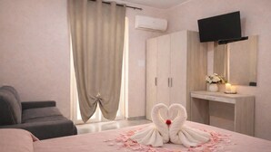 Ein Hotelzimmer mit Bett, Fernseher, Kleiderschrank und Schreibtisch mit Spiegel.