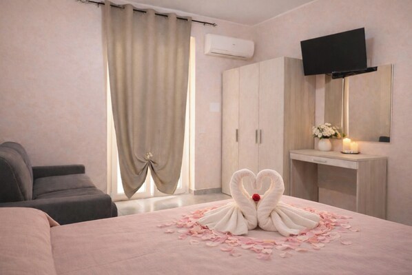 A hotel room with a bed, a TV, a wardrobe, and a desk with a mirror.