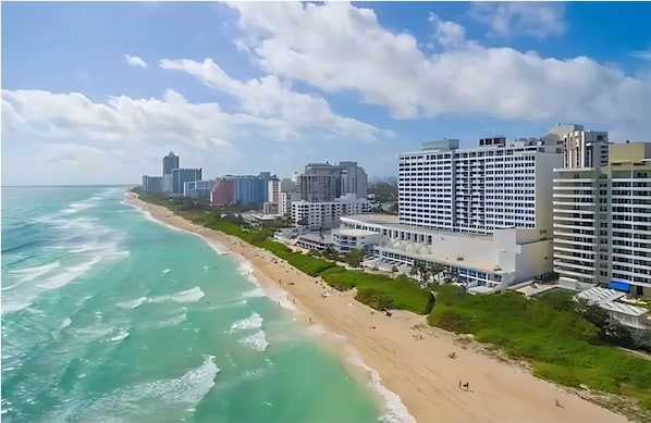 A coastal cityscape with a beach, high-rise buildings, and a clear sky.