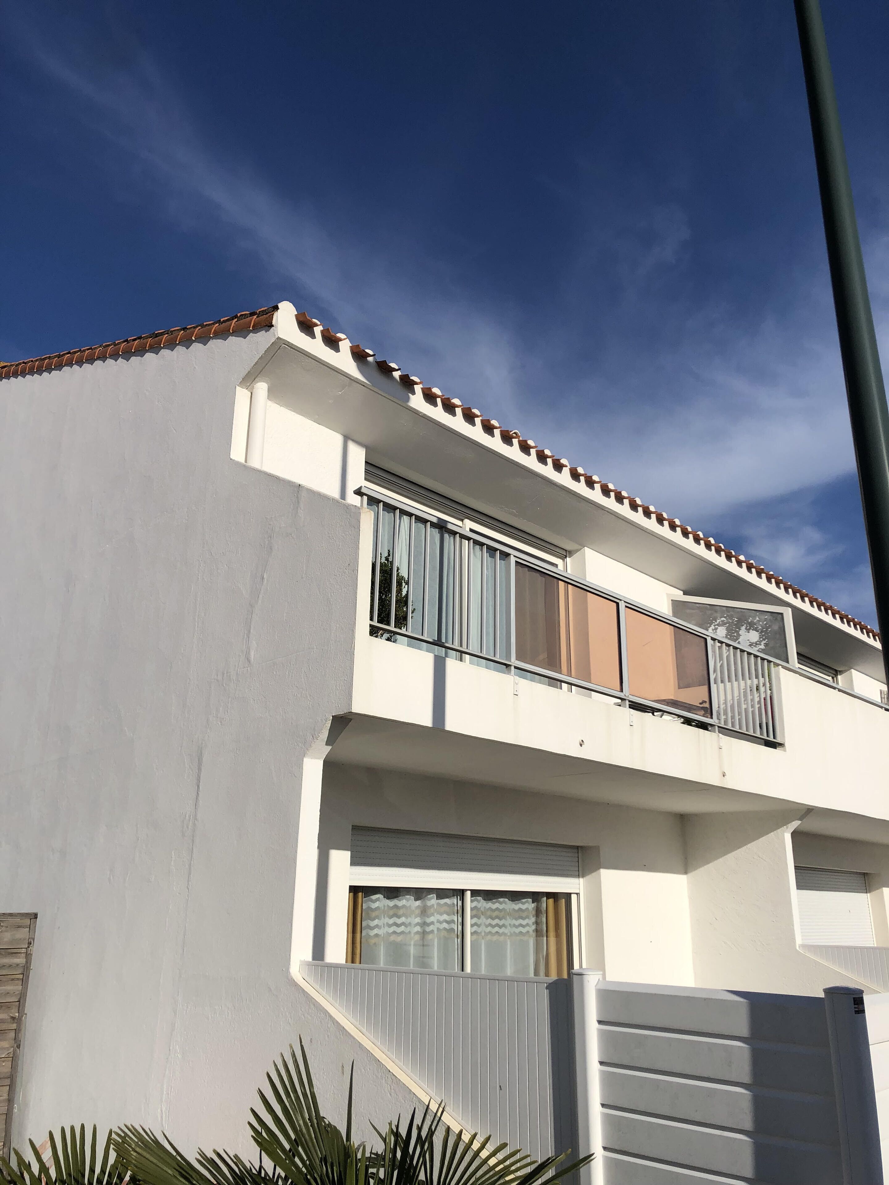 A modern two-story building with a flat roof, large windows, and a balcony.