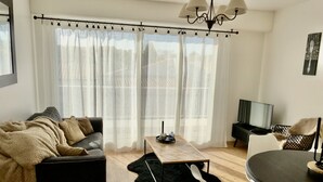 A modern living room with a sofa, a coffee table, a TV, and a dining area. - Lapart Challandais (Challans)