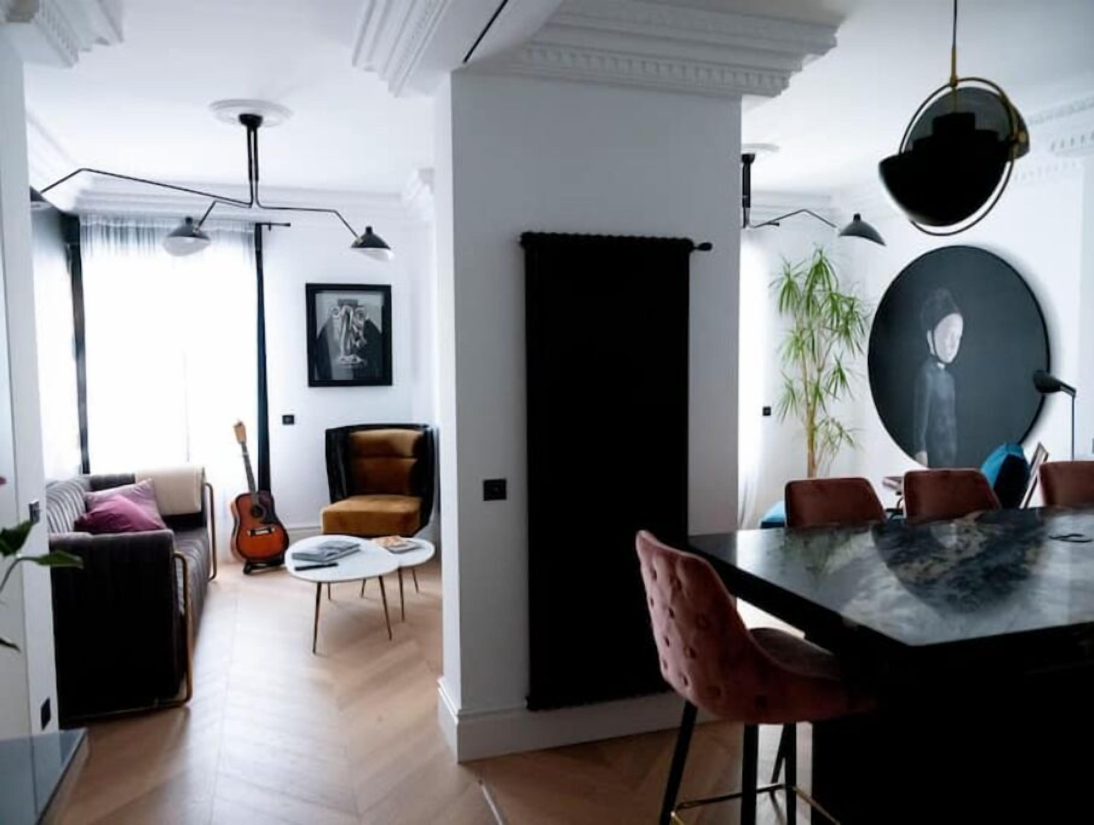 Una sala moderna con sofá, una guitarra, una silla y una mesa de comedor con sillas.