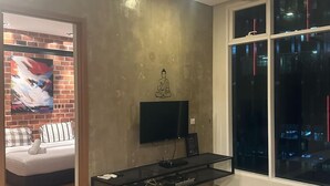 A modern living room with a flat-screen TV, a glass coffee table, and a large window with a city view. - Soho Suites KLCC by Inam Suites (Kuala Lumpur)