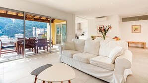 A modern living room with a white sofa, a small table, and a glass door leading to an outdoor seating area. - H2916 Holiday apartment Guillem in Cala San Vicente (Cala Sant Vicenç)