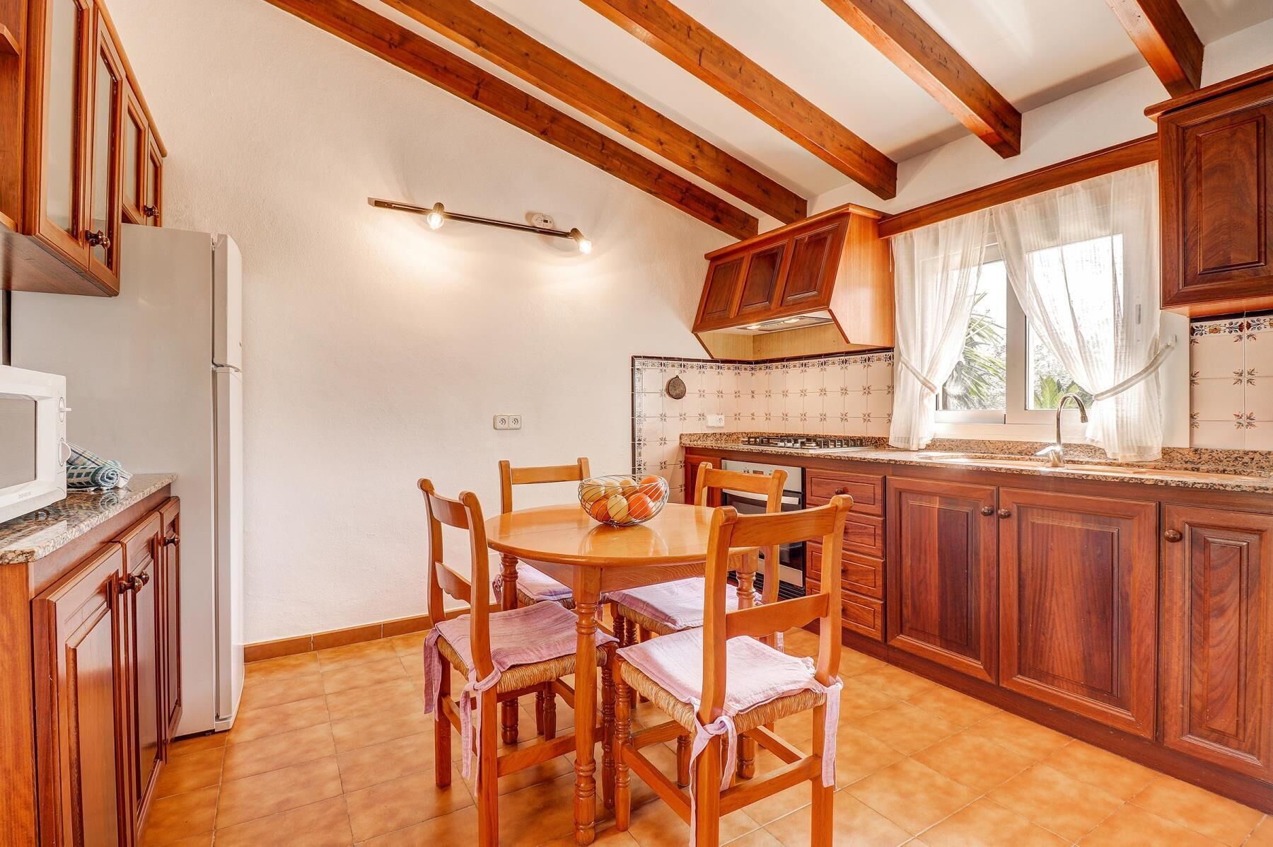 A kitchen with wooden cabinets, a tiled backsplash, and a dining table with chairs.