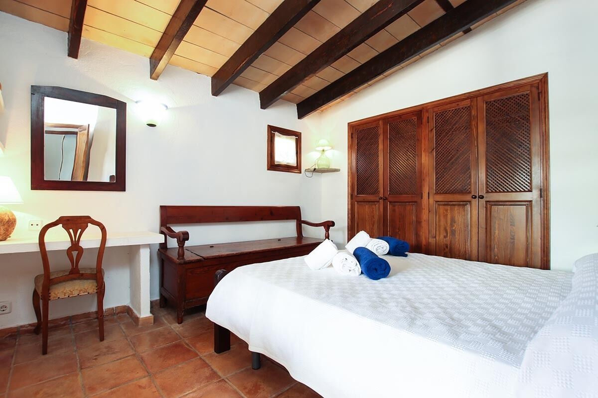A bedroom with a bed, wooden wardrobe, a desk, and a chair.