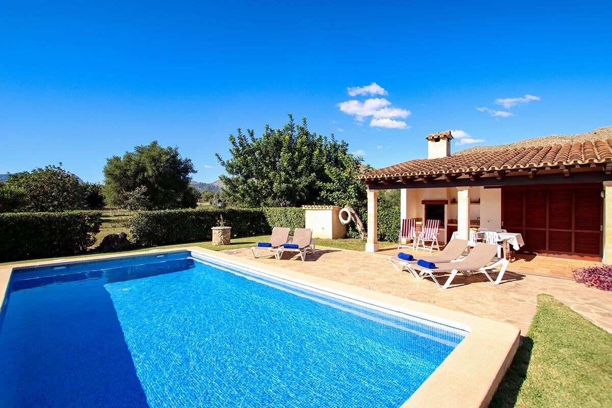 A swimming pool with lounge chairs and a covered patio area.