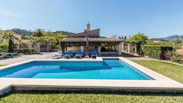 A swimming pool with a tiled deck, surrounded by a grassy area and a small building with a tiled roof. - H2924 Finca Catalina for 4 persons with pool near Pollenca (Pollenca)