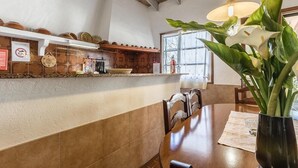 A dining area with a wooden table, chairs, a vase with flowers, and a hanging light fixture. - H2924 Finca Catalina for 4 persons with pool near Pollenca (Pollenca)
