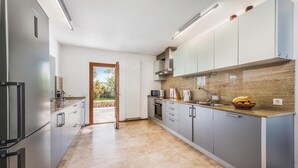 A modern kitchen with stainless steel appliances, grey cabinets, and a view to the outside. - H2903 Finca Creveta for 5 persons with pool in Pollenca (Pollenca)