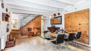 A spacious dining area with a glass table and modern chairs, a wooden accent wall, and a staircase leading to another level. - H2903 Finca Creveta for 5 persons with pool in Pollenca (Pollenca)