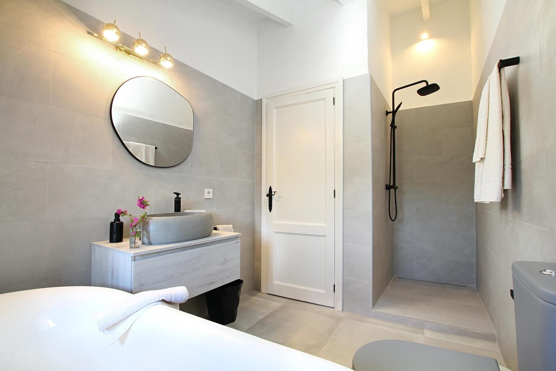 A modern bathroom with a round mirror, a sink, and a shower area.