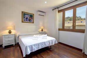 Quarto com uma cama, duas mesas de cabeceira, um quadro, ar condicionado e uma janela com vista.