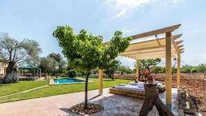 Zona piscina con un pergolato, un piccolo albero e una panchina in pietra.