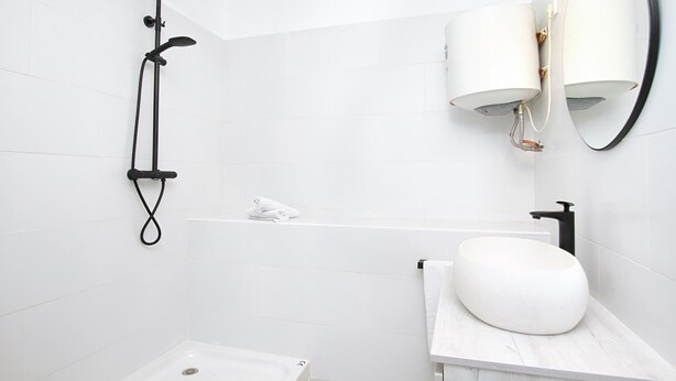 A modern bathroom with a shower, a toilet, a sink, and a mirror.