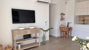 Ein modernes Wohnzimmer mit Fernseher, einer Holzkonsole und einem Essbereich mit Stuhl und Tisch.