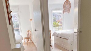 Ein heller, offener Wohnbereich mit großem Fenster, einem Bett, einem Sessel und einer Pendelleuchte.