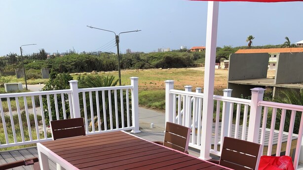 A wooden deck with a table and chairs, surrounded by white railings. - Very clean1 bedroom sleeps 4. Close to shopping and beach. Neighborhood setting  (Tanki Flip)