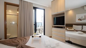 Een hotelkamer met een bed, een televisie, een bureau en een badkamer.