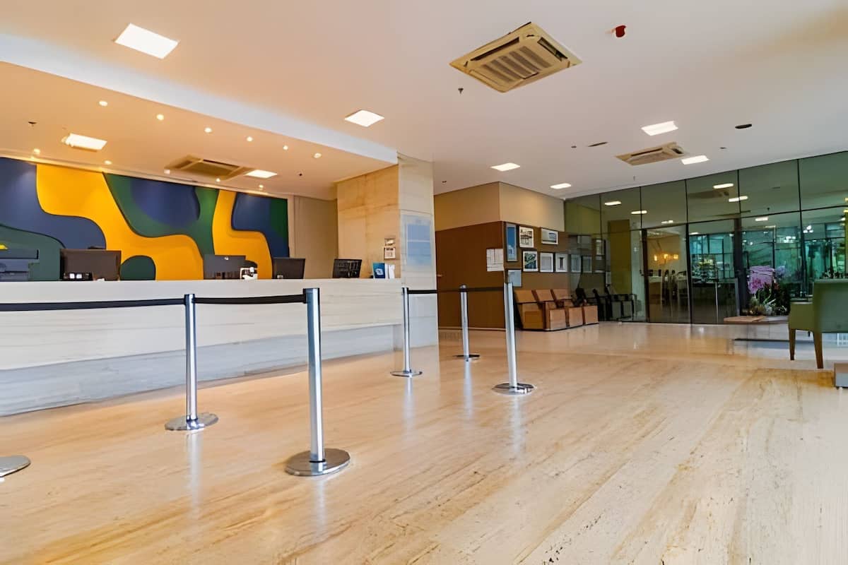 A reception area with a marble floor, a counter with a colorful abstract wall, and a glass door leading to another room.