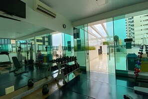 Ein modernes Fitnessstudio mit Trainingsgeräten, großen Fenstern und Blick auf umliegende Gebäude.