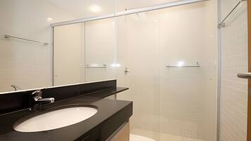 A modern bathroom with a black countertop, a white sink, and a glass shower enclosure.