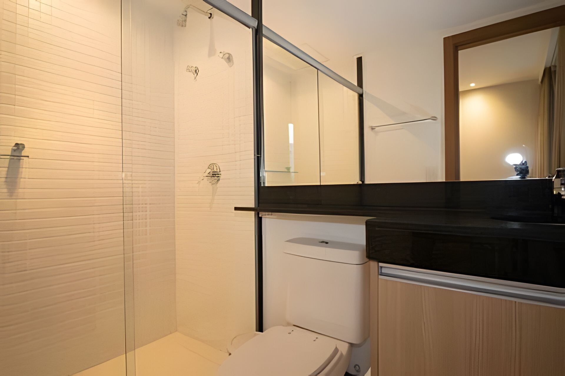 A modern bathroom with a shower, toilet, and sink.