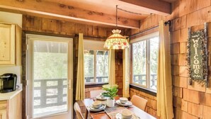 A wooden cabin interior with a dining table set for four, a coffee maker, and a 'Welcome' sign on the wall.