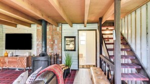 A cozy living room with a fireplace, a television, and a staircase with plaid carpet.