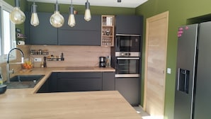 Una cocina moderna con armarios negros, encimera de madera y horno empotrado.