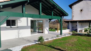 Una casa moderna con techo verde, amplios ventanales y un patio con piedras blancas y plantas.