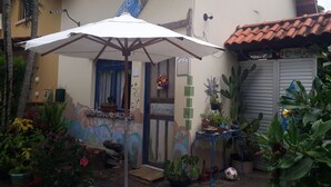 A courtyard with a white umbrella, a door with a 'Welcome' sign, and various potted plants. - Casa Hostel Mosaicos DyA (Florianópolis)