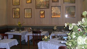 A restaurant interior with multiple tables set for dining, wooden panel walls, and framed landscape paintings. - Hôtel Aux Armes d'Estaing (Estaing)