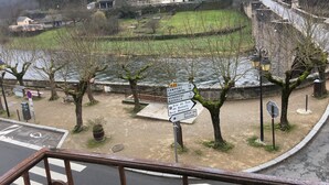 A riverside view with a signpost indicating directions to various destinations including a museum and a tourist office. - Hôtel Aux Armes d'Estaing (Estaing)