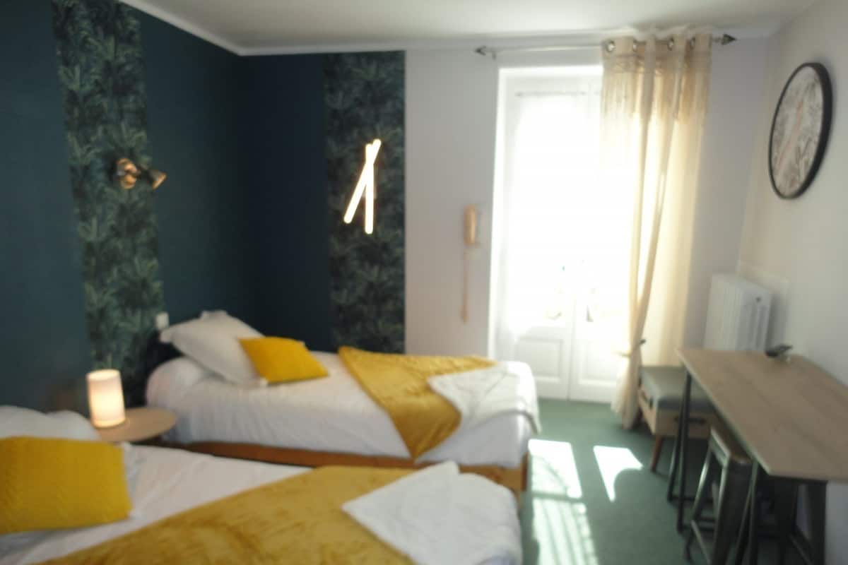 A room with two beds, a table, and a chair.