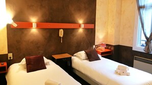 A hotel room with two beds, a telephone, a nightstand, and a window with curtains. - Hôtel Aux Armes d'Estaing (Estaing)