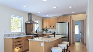 Una cocina moderna con armarios de madera, una estufa de acero inoxidable y una isla grande con taburetes de bar.