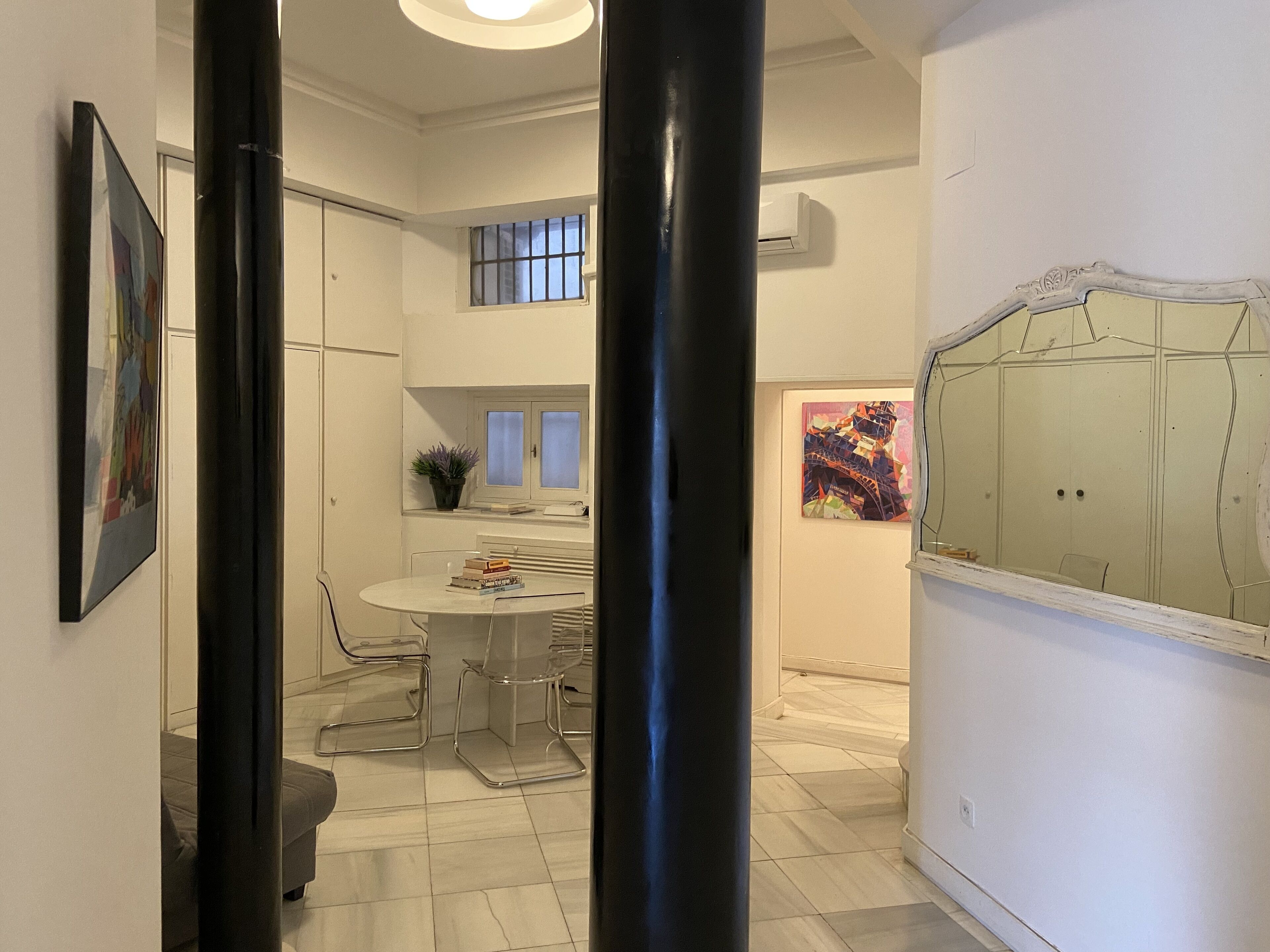 A modern interior with a dining area, a large window, and a unique wall art piece.