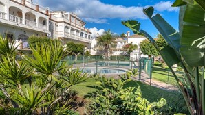 A courtyard with a swimming pool, surrounded by lush greenery and traditional architecture. - CALLE COMPETA 11 (LAS LAGUNAS DE MIJAS,)
