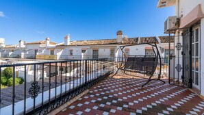 A balcony with a checkered floor, a metal railing, and a swing chair. - CALLE COMPETA 11 (LAS LAGUNAS DE MIJAS,)