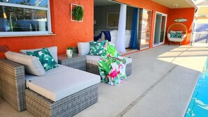 Un espace extérieur aménagé, abrité et doté de meubles en osier, ainsi qu’une piscine.