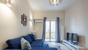Ein modernes Wohnzimmer mit einem blauen Sofa, einem Flachbildfernseher und einem weißen Couchtisch.