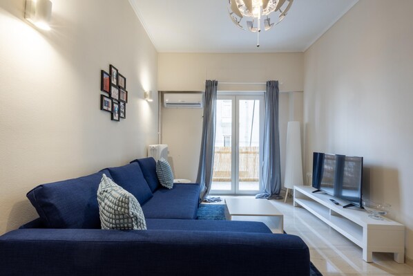 A modern living room with a blue sofa, a flat-screen TV, and a white coffee table. - Superb Family Apt In The Center Of Athens (Athens)